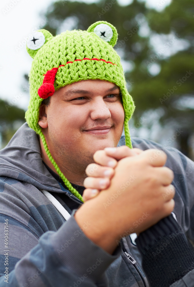 Playful rivalry. A young man wearing a frog-shaped cap busy arm wrestling outside.