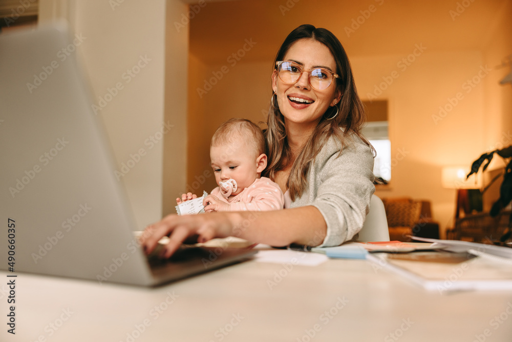 Happy single mom typing on a laptop in her home office