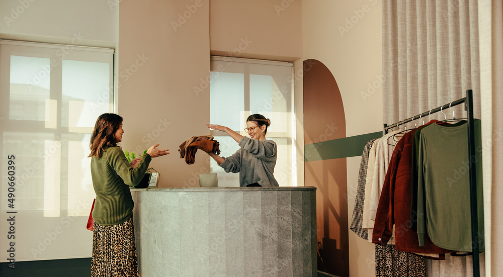 Friendly shop owner assisting a female customer at the counter