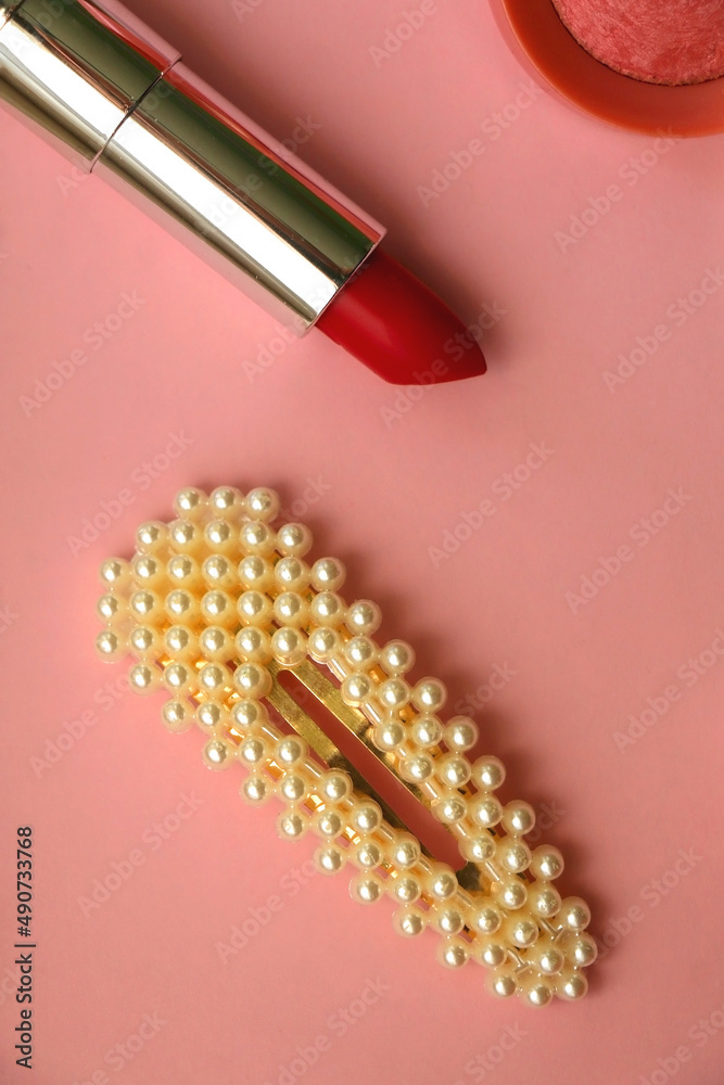 Pearl hair clip, red lipstick and pink blush on bright pink background. Flat lay.