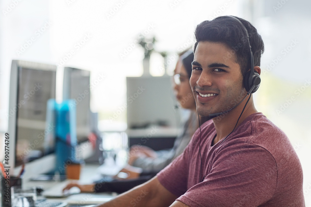 Hes next in line for a promotion. Shot of a young man wearing a headset with his colleagues blurred 