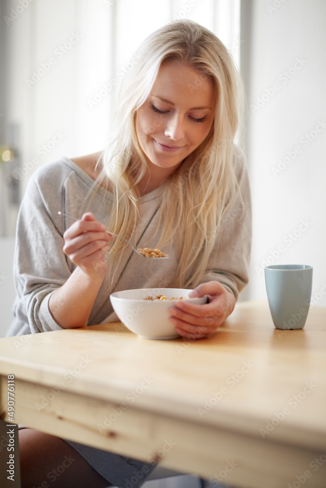 这是一个很好的开始新一天的方式。一个漂亮的年轻女人一边喝着咖啡一边享用早餐。