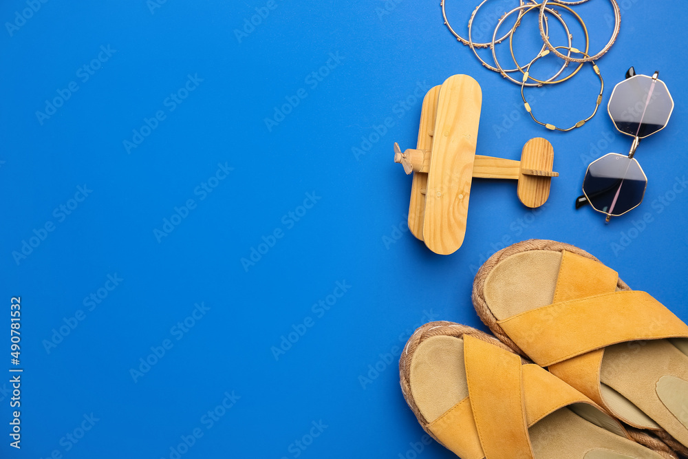 Stylish shoes, accessories and wooden plane on color background