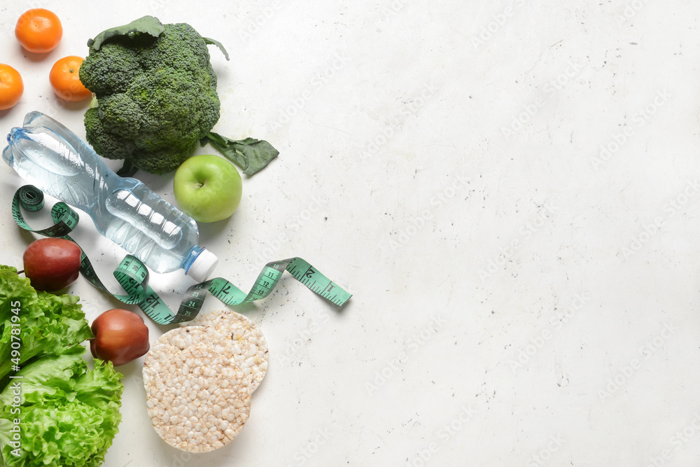 Composition with bottle of water, measuring tape, vegetables and fruits on light background