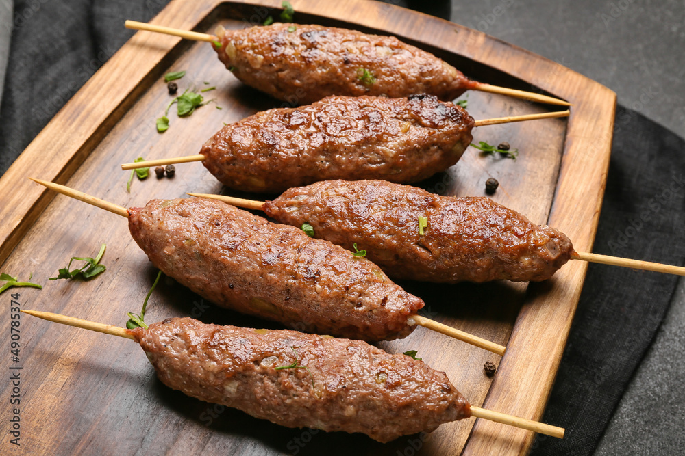 Wooden board of skewers with tasty lula kebab on table