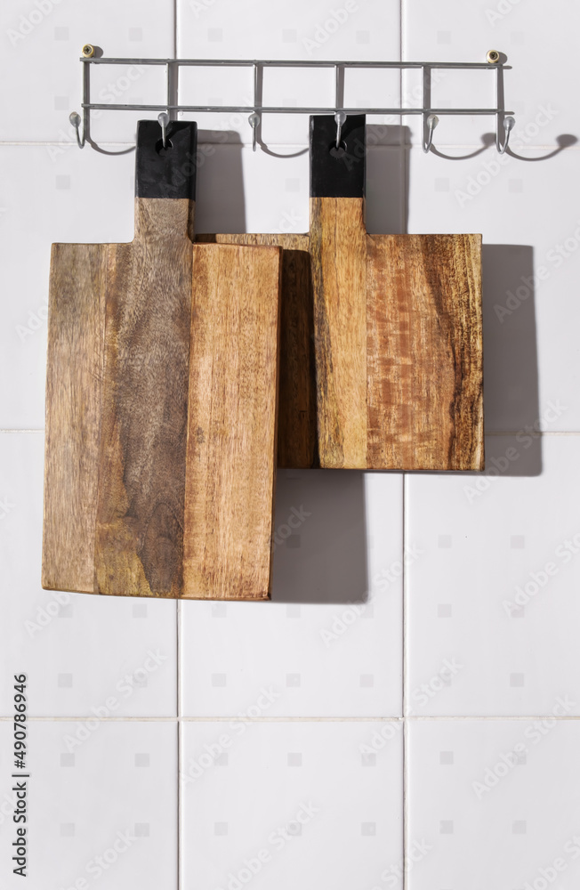 Wooden cutting boards hanging on white tile wall