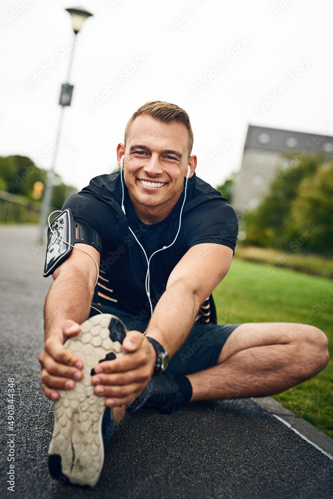 Make a difference by going the distance. Portrait of a sporty young man stretching before a run outd