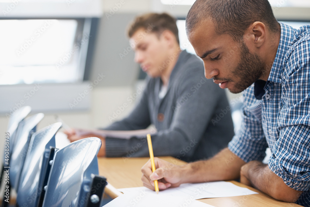 It all comes down to the test.... Two male students writing exam in a lecture hall.