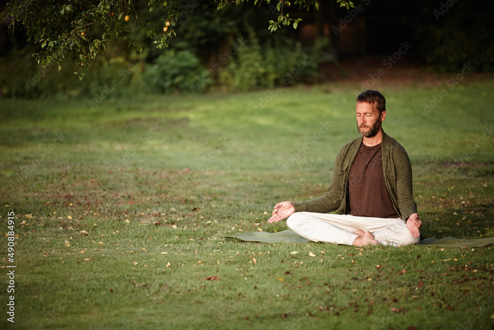 Finding peace of mind in nature. Shot of a handsome mature man meditating in the lotus position in t