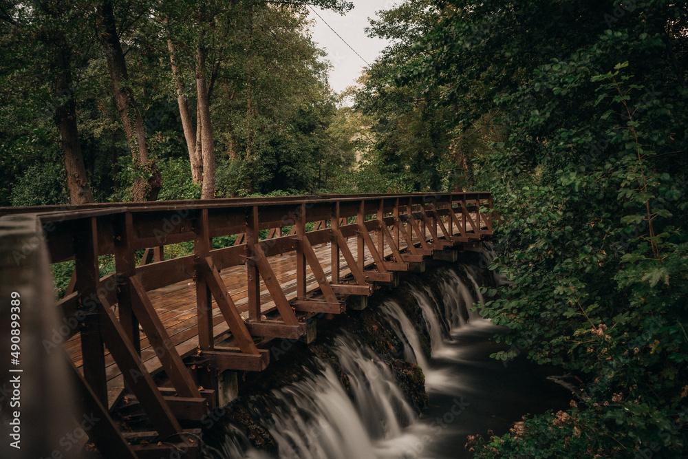 Beautiful view of the wooden bridge over the waterfall in the green forest.