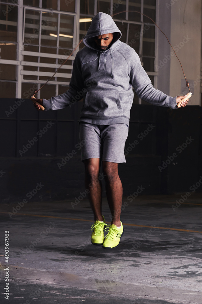 Increasing his focus and stamina. Shot of a young man training with a skipping rope.