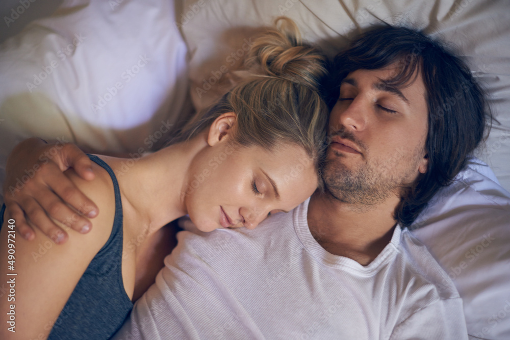 Safe in his arms. Cropped shot of a young woman sleeping on her boyfriends shoulder in bed.