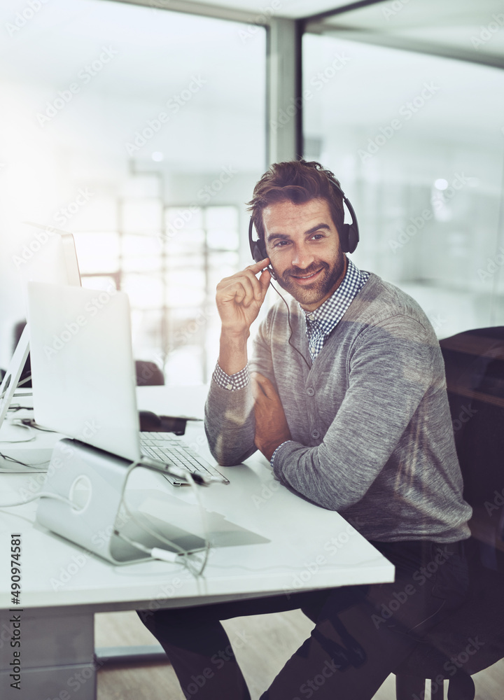 Service with a smile. High angle shot of a handsome young businessman wearing a headset while sittin