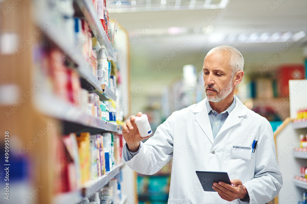 This doesnt belong here.... Cropped shot of a handsome mature male pharmacist using a tablet while w