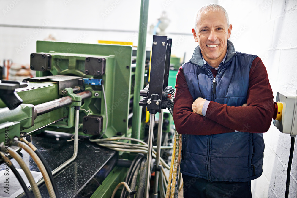 Everything is in perfect condition. Portrait of a mature man standing next to machinery in a factory