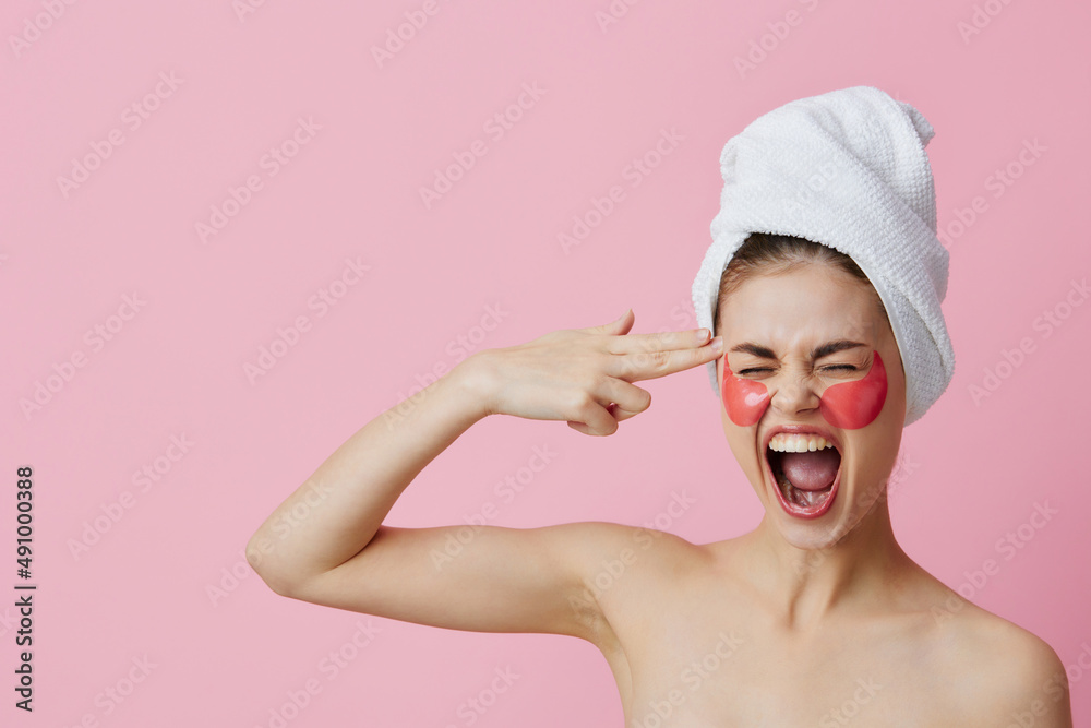 portrait woman pink patches on the face with a towel on the head pink background