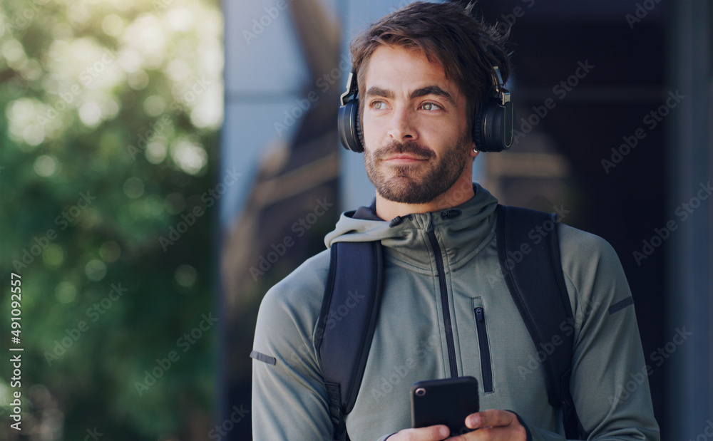 一个好的播放列表就是你所需要的。一个男人戴着耳机走在外面用手机的镜头