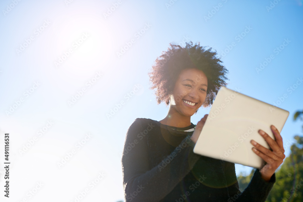 在阳光下上网。一位年轻漂亮的女士在外面用平板电脑的低角度镜头。