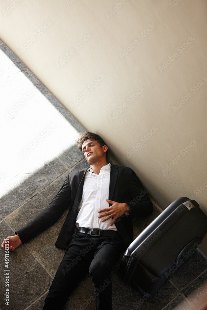 Completely and utterly exhausted. Shot of an exhausted young businessman lying on the floor beside h