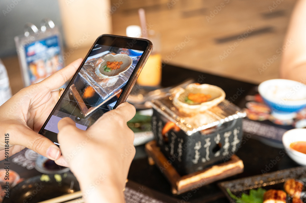 Hand of female taking a photo by smart phone with Kani Miso, Steamed crab meat on fire stove in japa