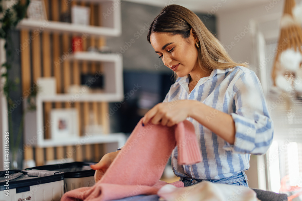 漂亮的金发女人，洗完衣服后叠好衣服。