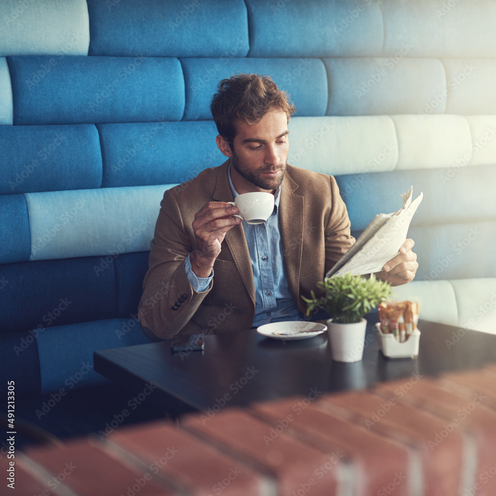 他喜欢自己的新闻在媒体上热传。一个英俊的男人在喝咖啡休息时看报纸的镜头