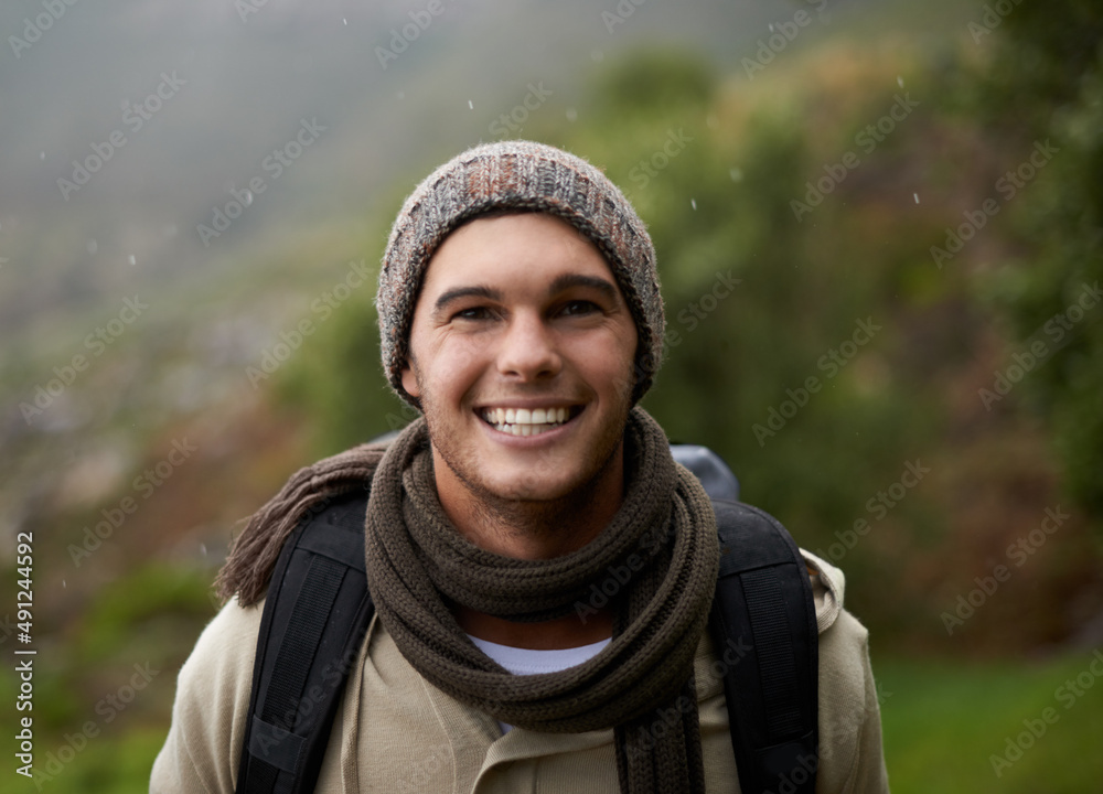 He has a great love for the outdoors. Portrait of a handsome young man standing in the mountains.