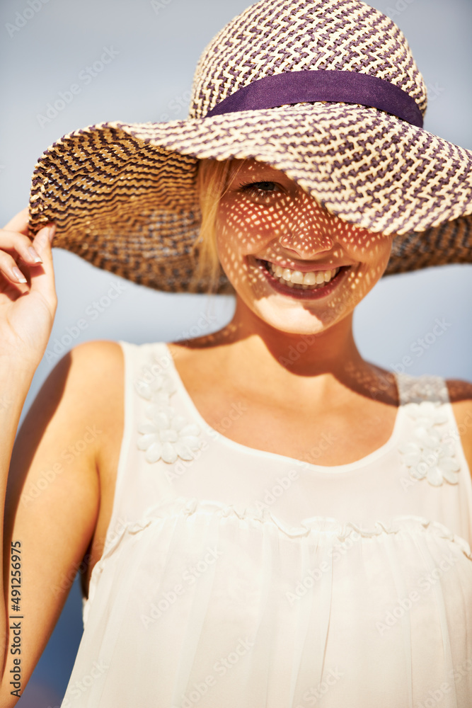 Feeling summery. A gorgeous young woman wearing a straw hat in the summer sun.