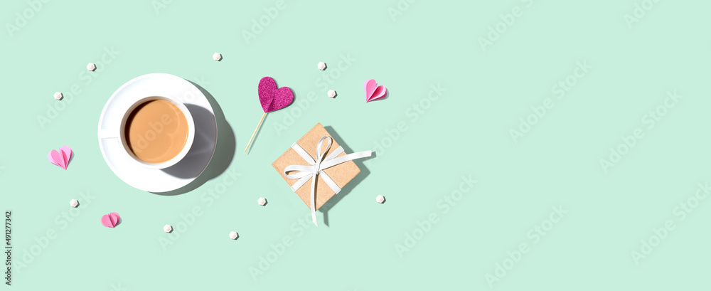 A cup of coffee with a gift box and hearts - flat lay