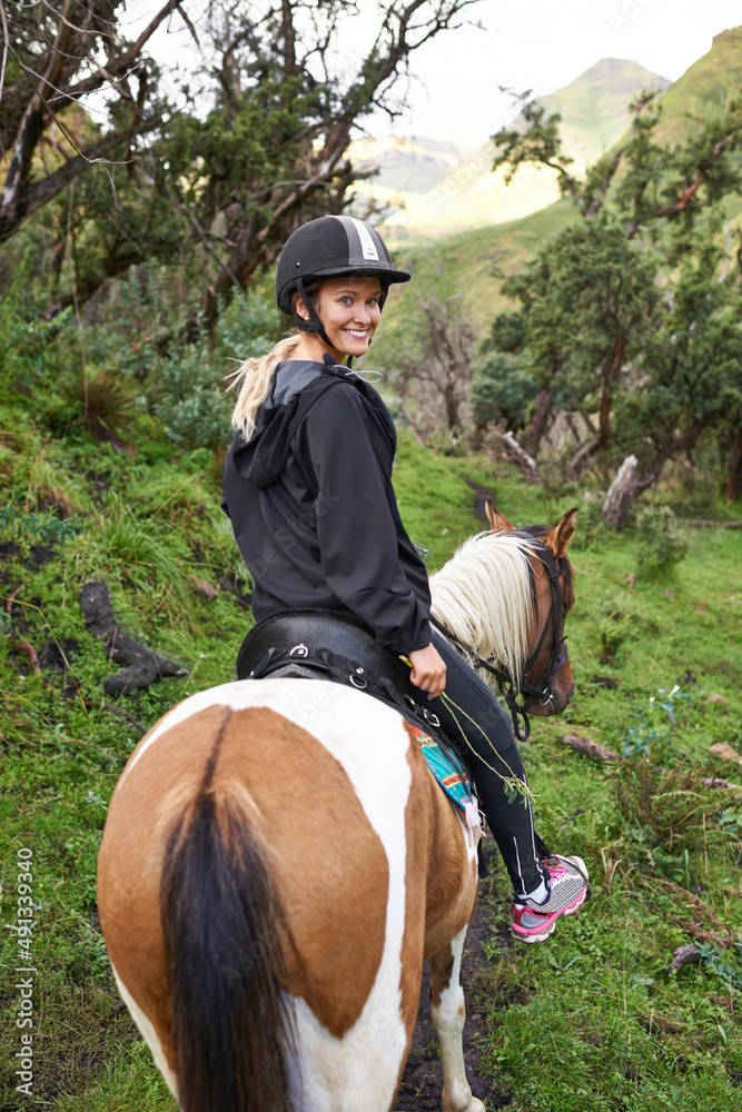 Horse riding in the outback. An attractive young woman riding a horse on a mountain trail.