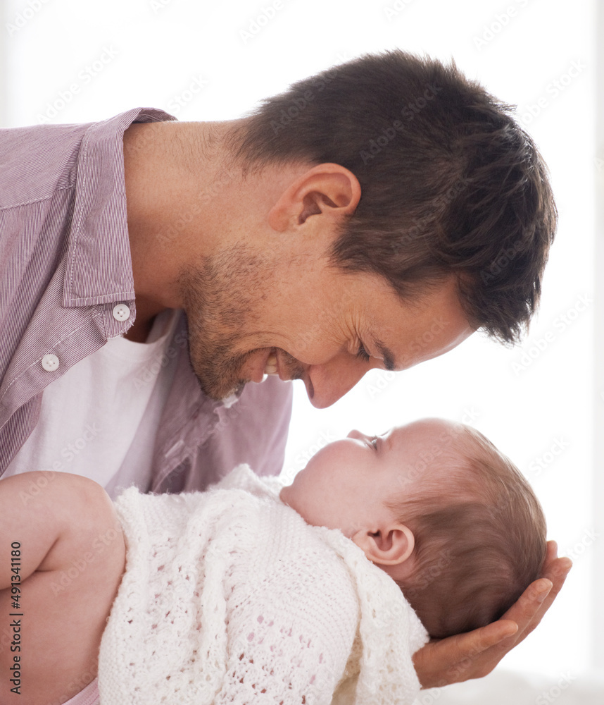 Daddys little angel. Side view of a young father holding and looking at his adorable baby girl.