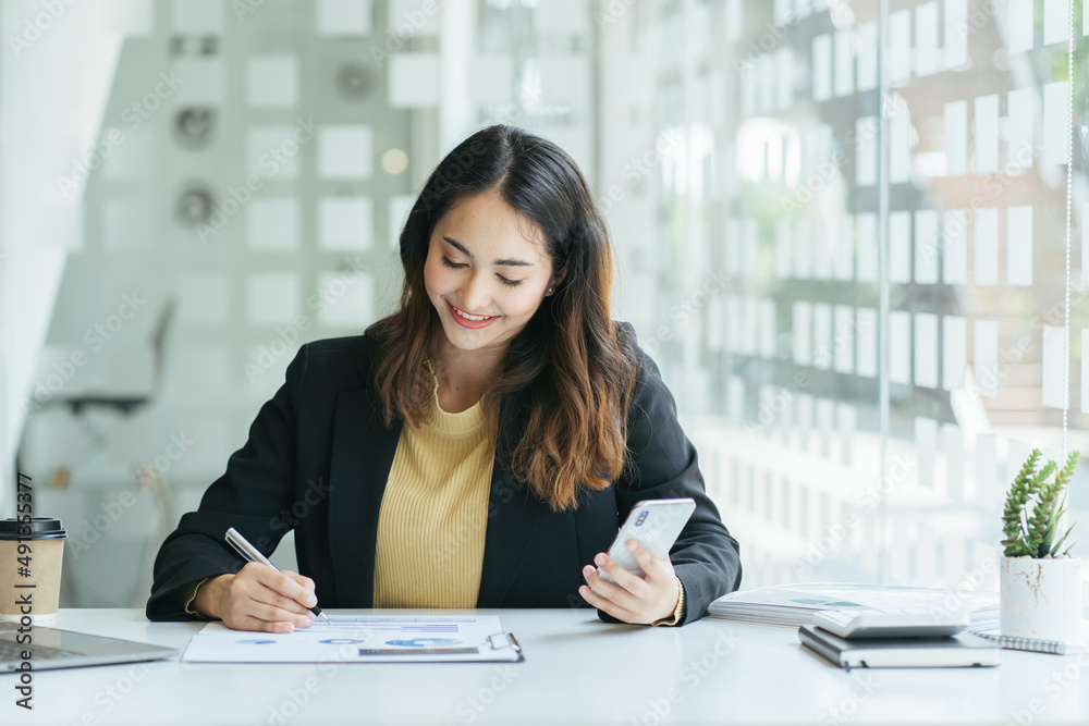 Serious Indian businesswoman talking on cellphone, writing notes on colorful sticky papers in office