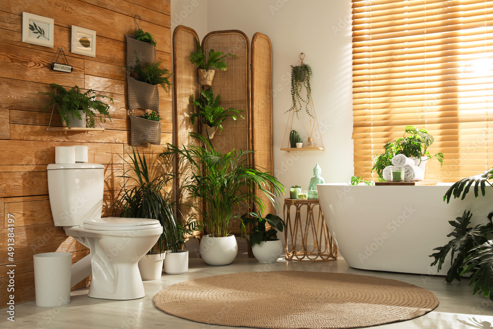 Stylish bathroom interior with toilet bowl and green plants