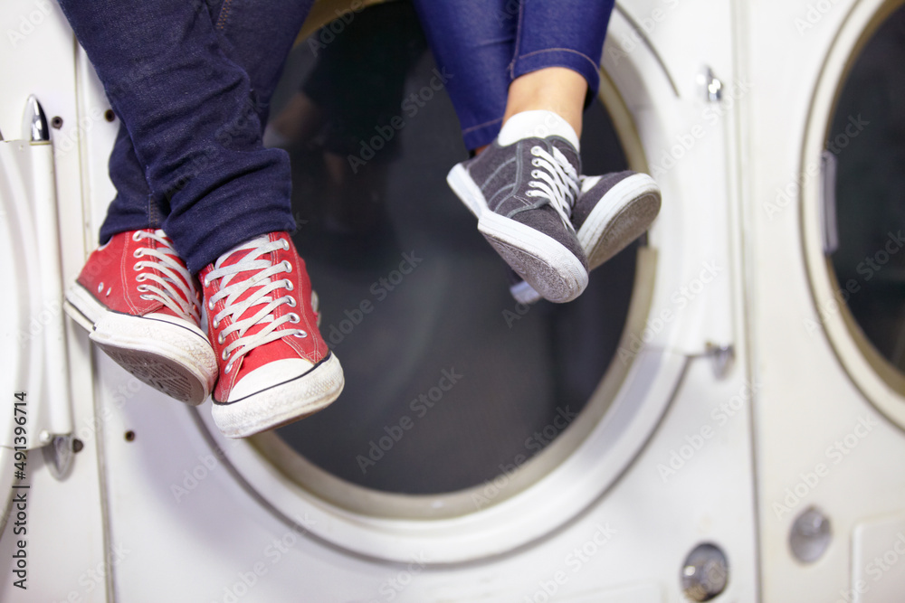 Theyre relaxed while doing laundry. Cropped image of a couples feet as they sit on a washing machine