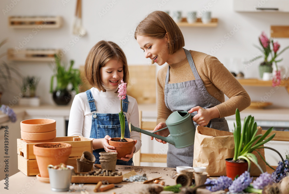 Mother and daughter watering plant together