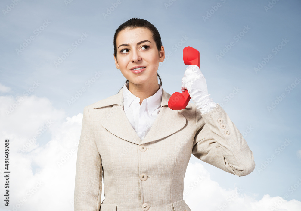 Attractive young woman holding red retro phone.