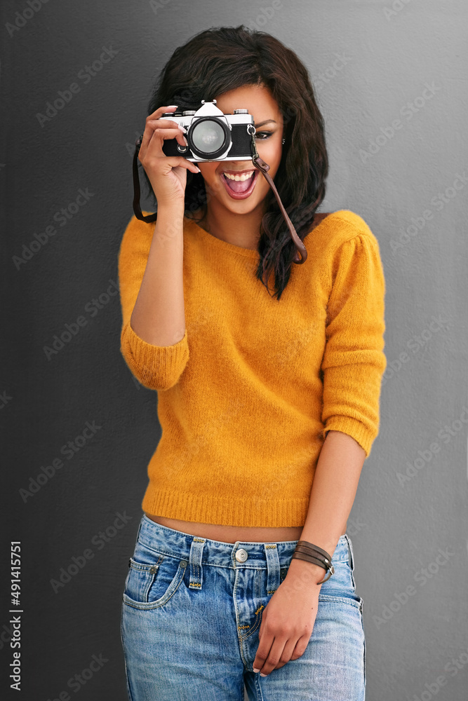 Thats what I like to see. Studio shot of a young woman using a vintage camera against a gray backgro