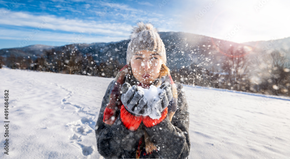 Girl blowing on snow magic frozen flakes in the air