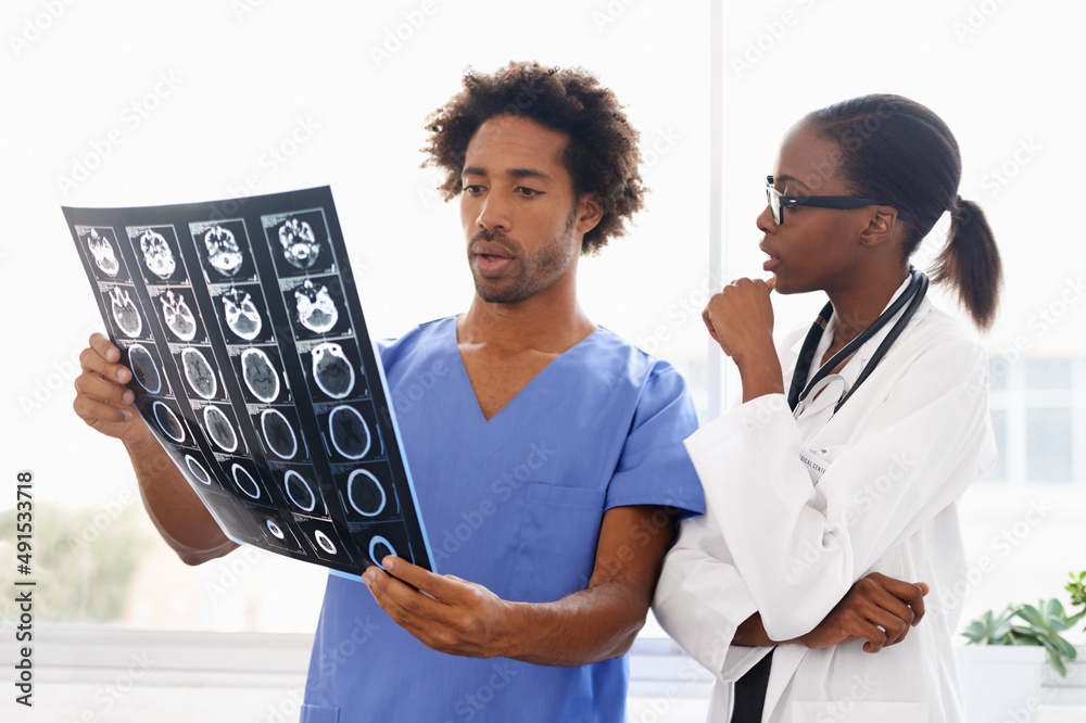 Learning how to read scans. Shot of a female doctor and male nurse studying a CAT scan.