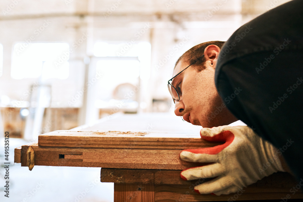 I like having a dust-free working environment. Shot of a handsome young carpenter blowing dust off a