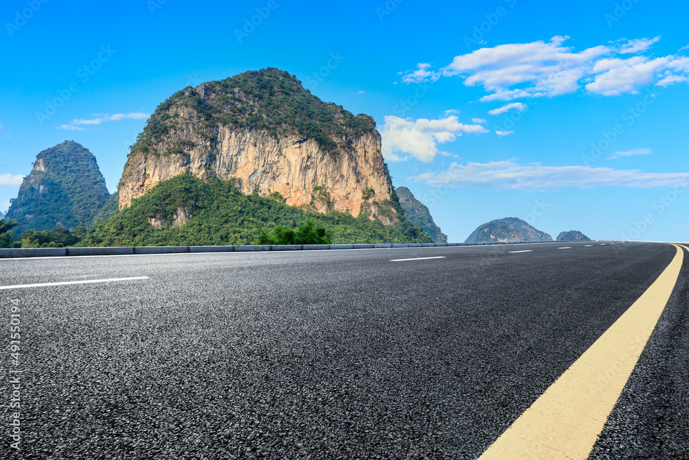 夏日蓝天下的沥青公路和山地自然风光。公路和山地背景。