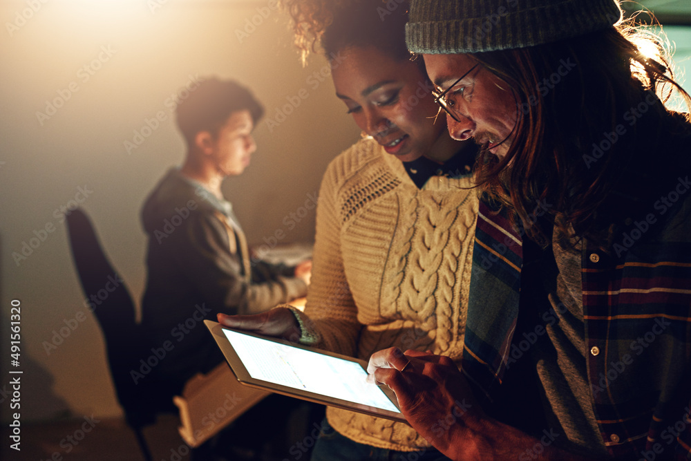 Doing whatever it takes to get the job done. Shot of two coworker discussing something on a digital 