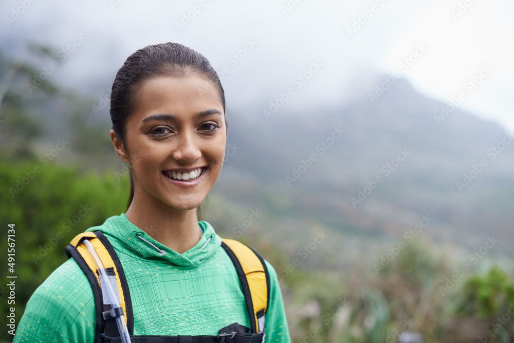 她喜欢越野跑。一个美丽的年轻女子站在风景优美的山脉背景下。