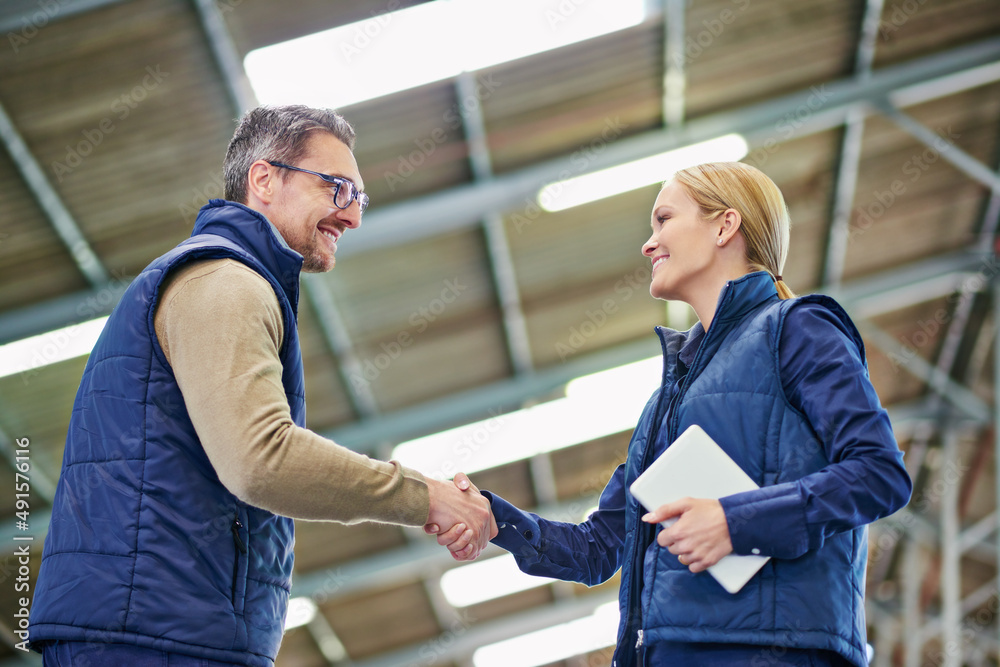 Youre going to do great here. Shot of two people shaking hands in a large warehouse.