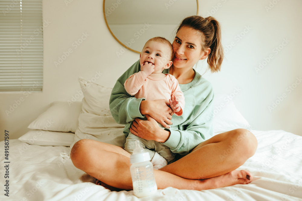 Happy mother holding her baby on the bed