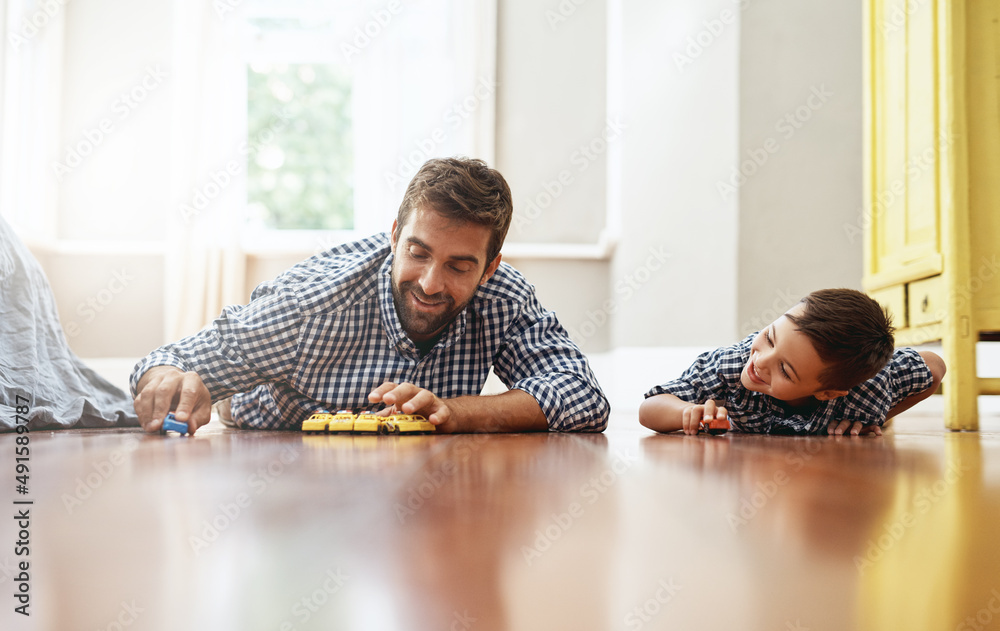 Dad always make time to play with me. Shot of a young boy and his father playing with cars on the fl