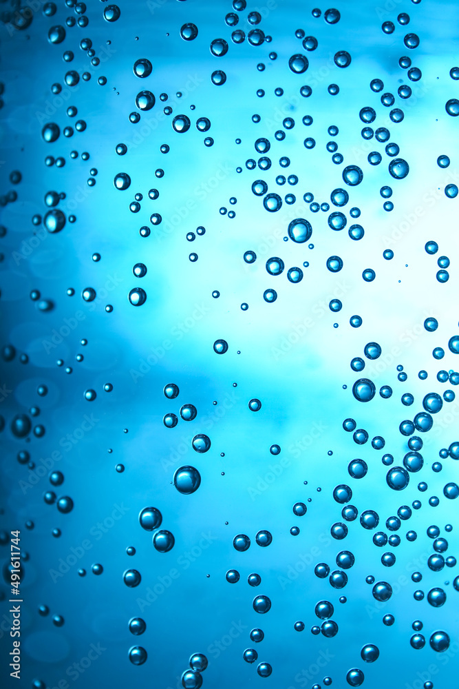 Clear water with bubbles on blue background, closeup