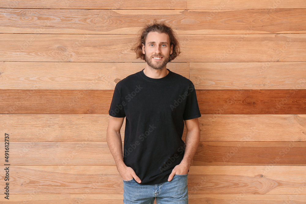 Handsome young man in black t-shirt on wooden background