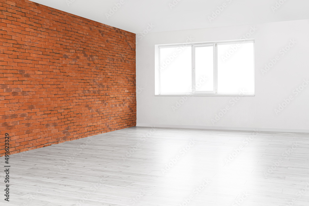 View of big empty room with window, light and brick walls