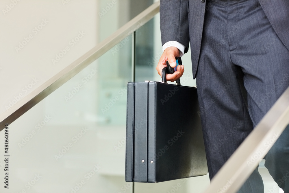 Business man carrying a cellphone and suitcase. Low section of business man carrying a cellphone and